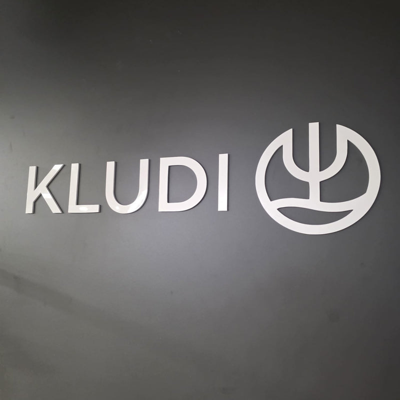 Logotip Kludi od srebrnog pleksiglasa na zidu