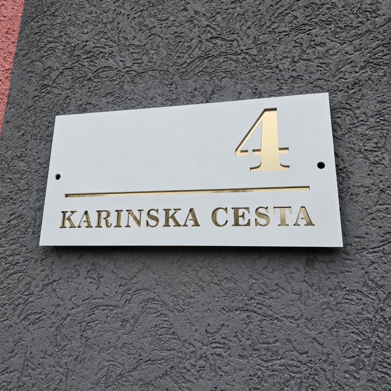 Bijela ploča s kućnim brojem i zlatnim slovima